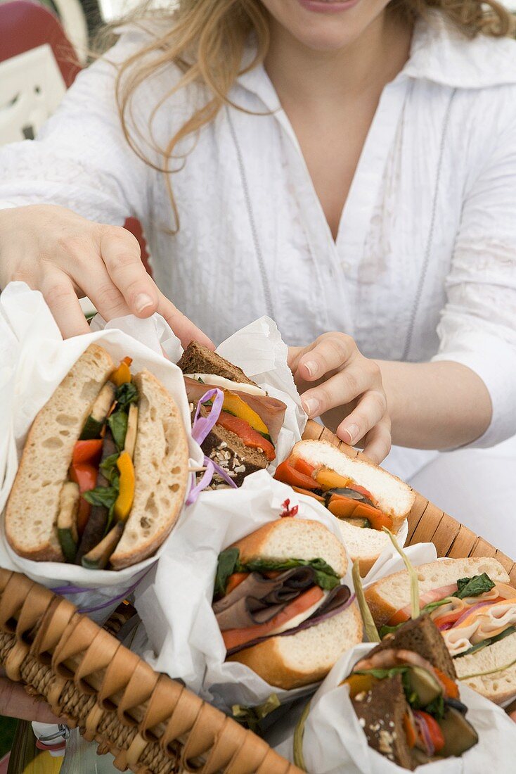 Frau greift nach Sandwich im Picknickkorb