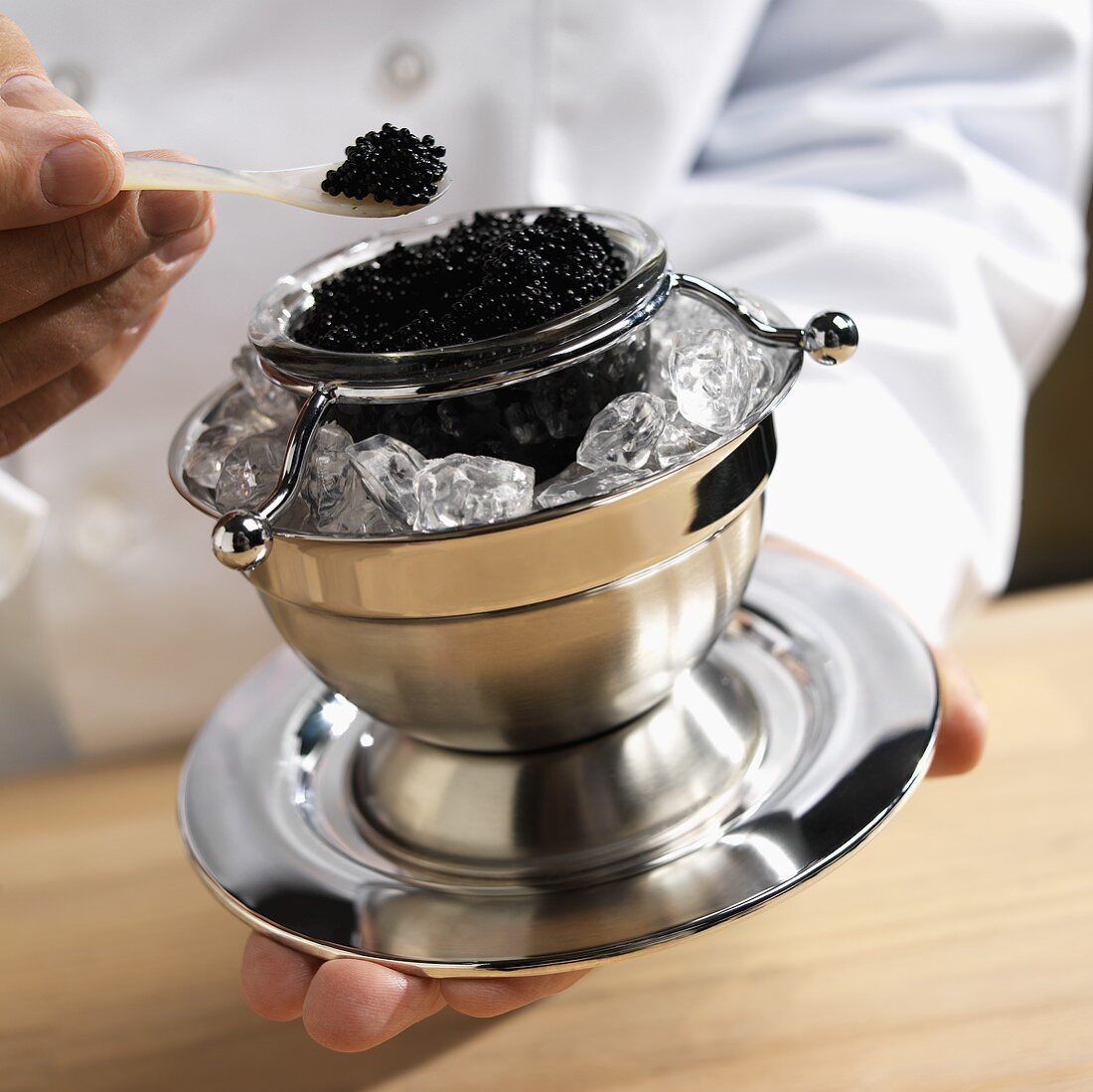 Koch hält Schale mit schwarzem Kaviar