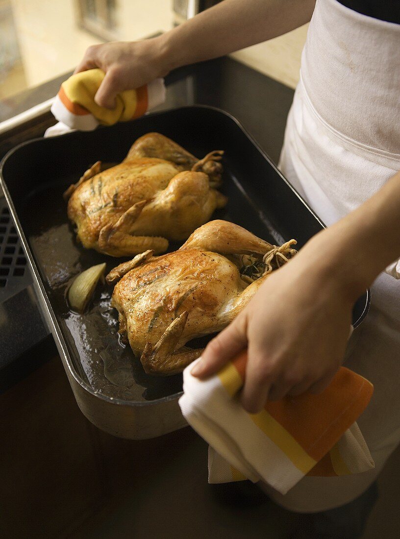 Chef Carrying Roasting Pan with Two Herb Roasted Chickens