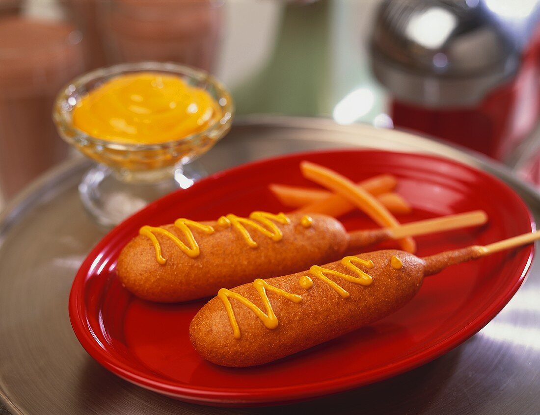 Two Corn Dogs with Mustard on a Red Plate