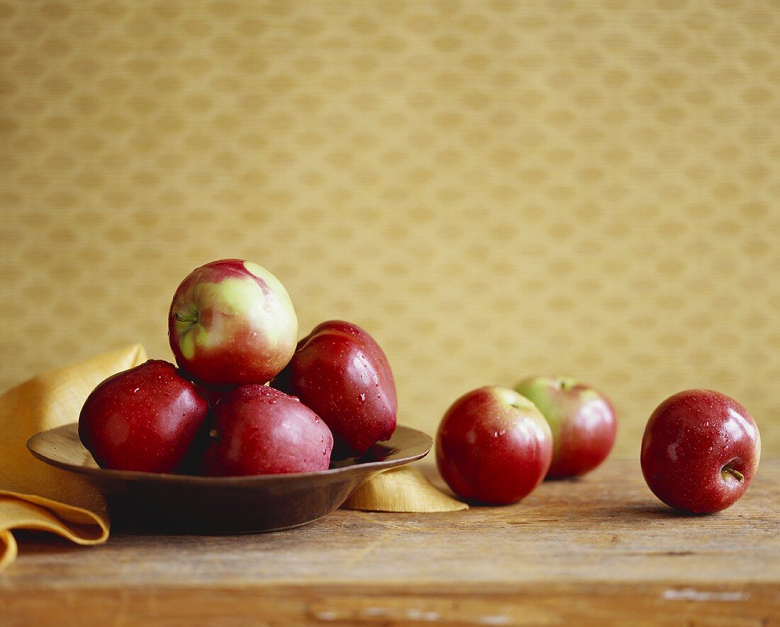 Frisch gewaschene Äpfel auf und neben einem Teller