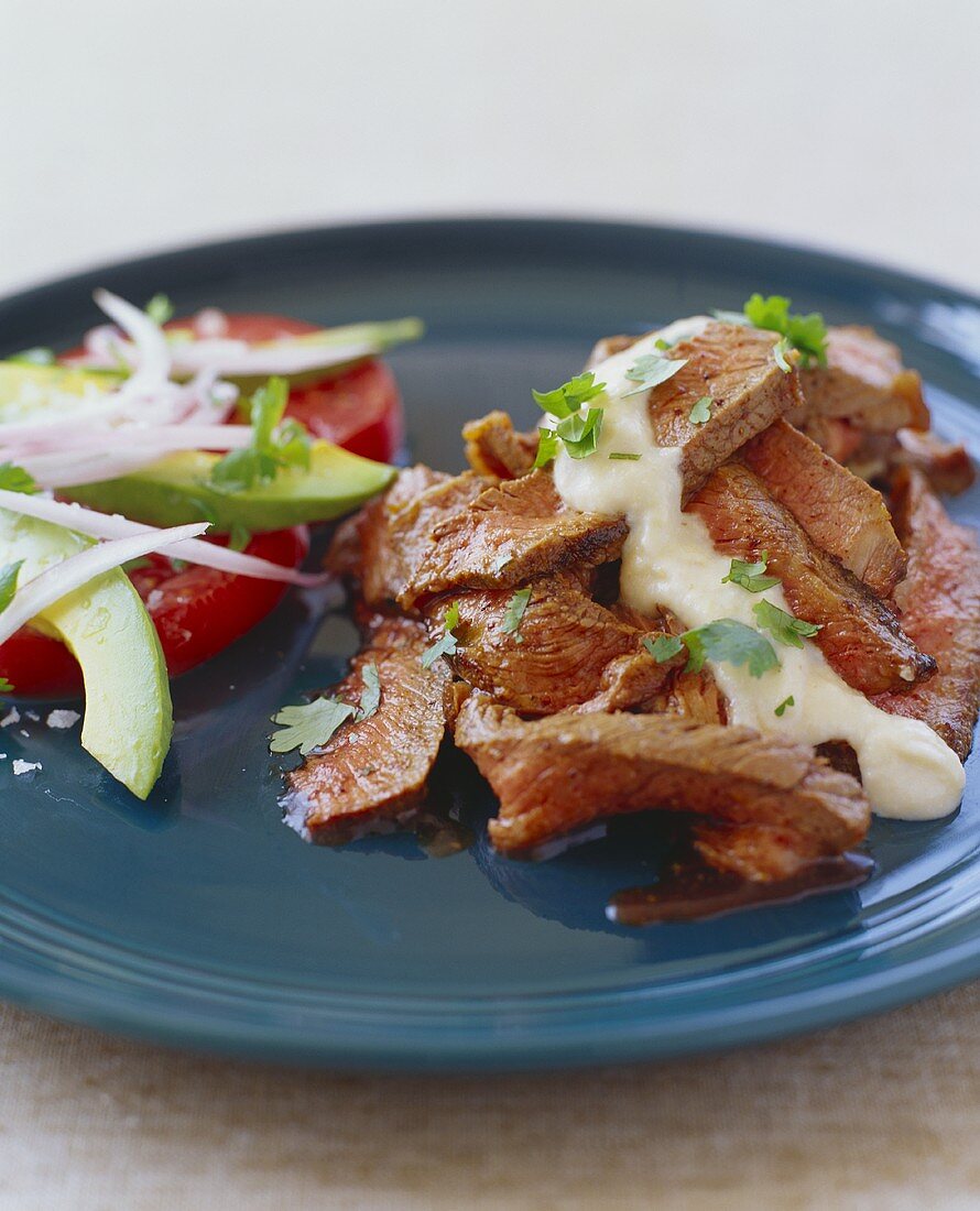 Rindersteak in Scheiben mit Sauce und Avocadosalat