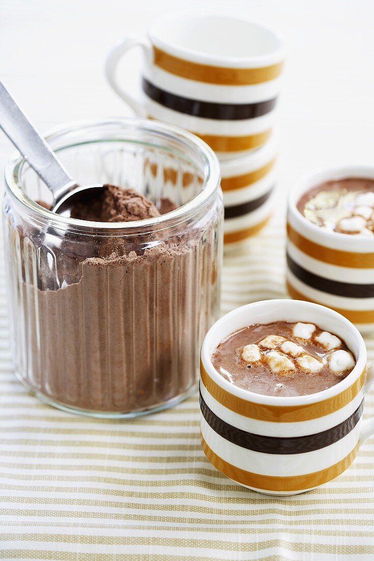 Zwei Tassen Kakao mit Mini-Marshmallows, Kakaopulver im Glas
