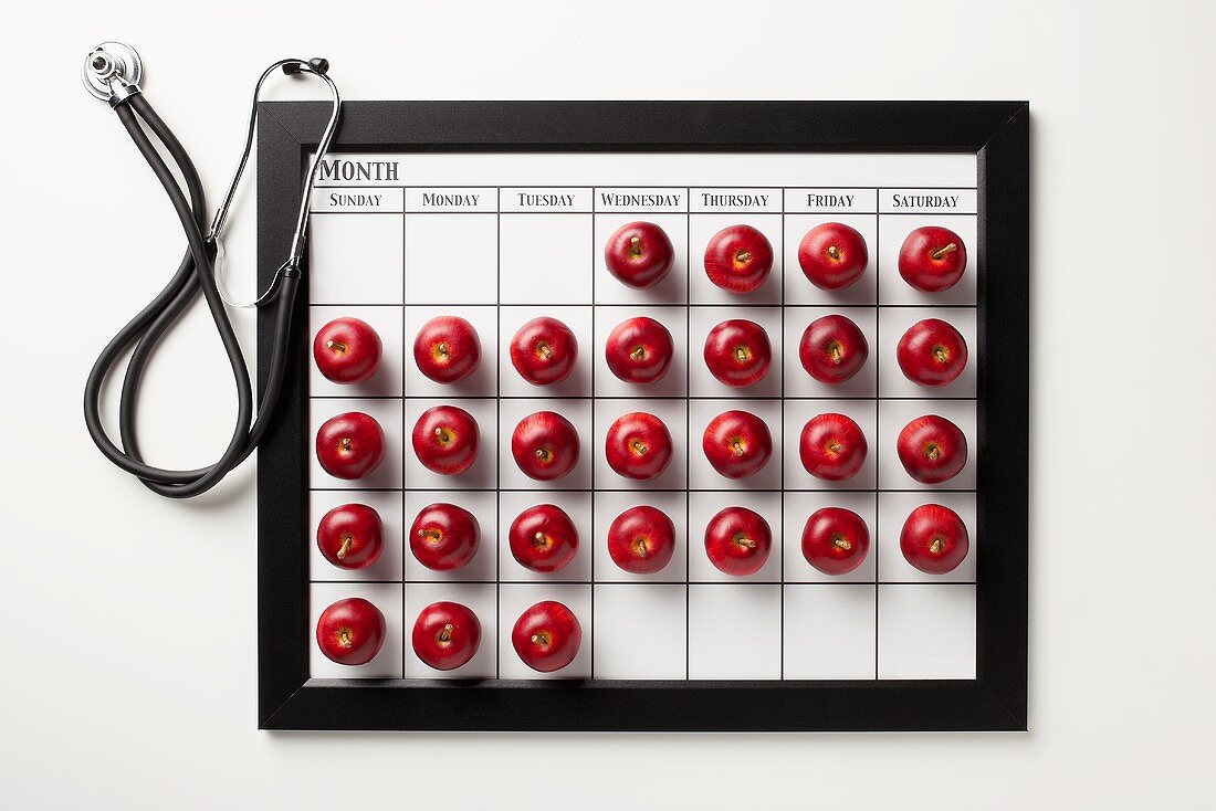 Kalender mit roten Äpfeln und Stethoskop