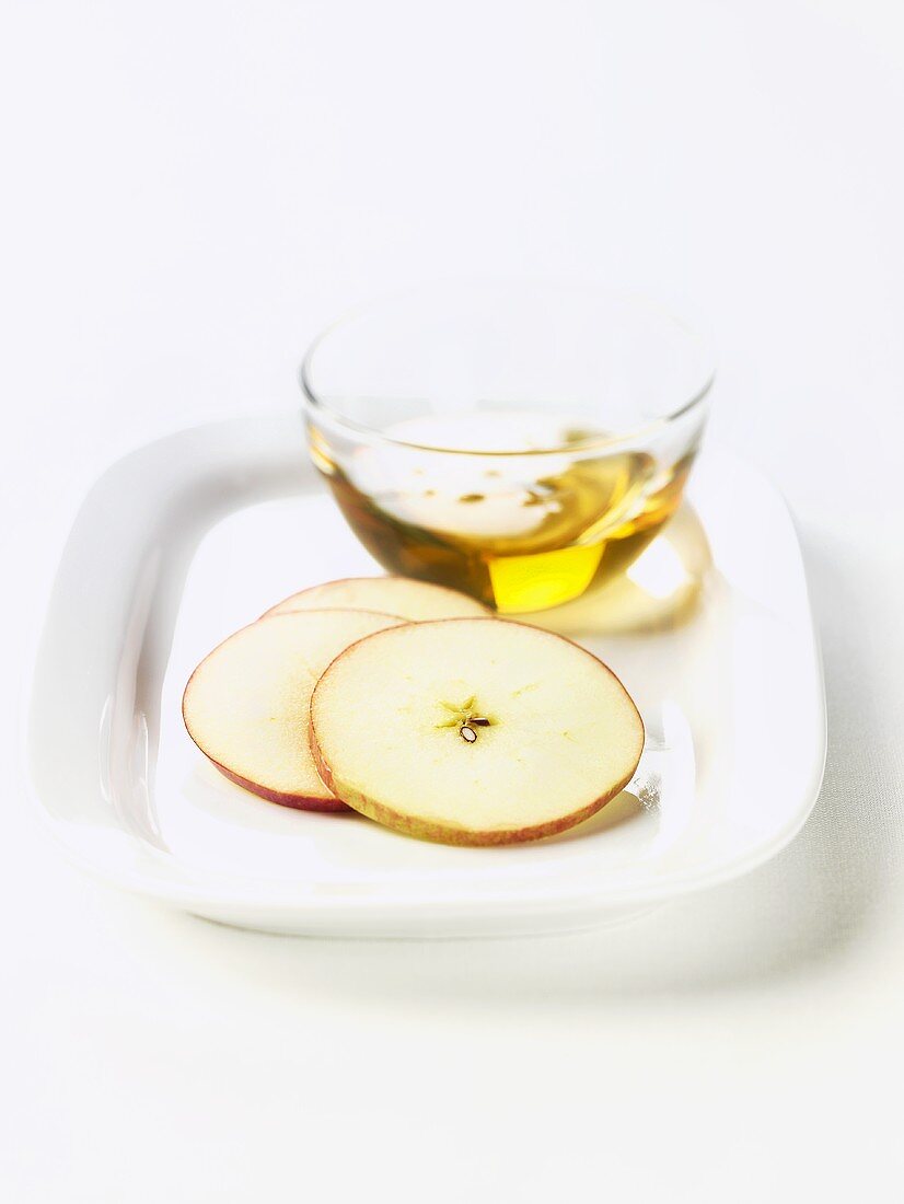 Ein Glasschälchen Apfelsaft mit Apfelscheiben auf Teller