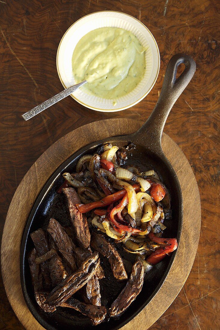 Gebratenes Rindfleisch mit Zwiebeln, Paprika und Avocado-Dip