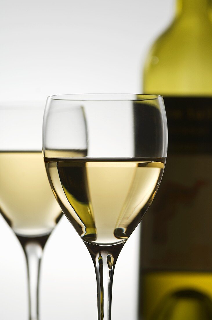 Zwei Gläser Weißwein vor Weissweinflasche