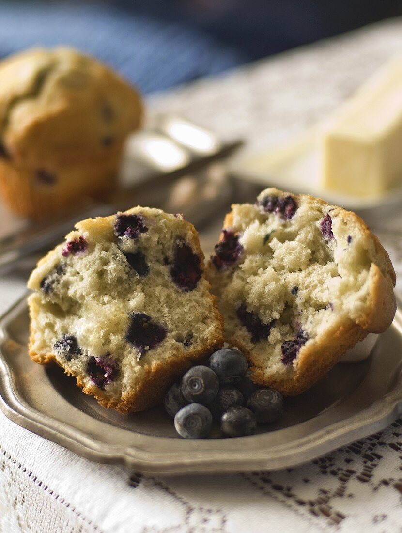 Halved Blueberry Muffin on a Plate with Fresh Blueberries