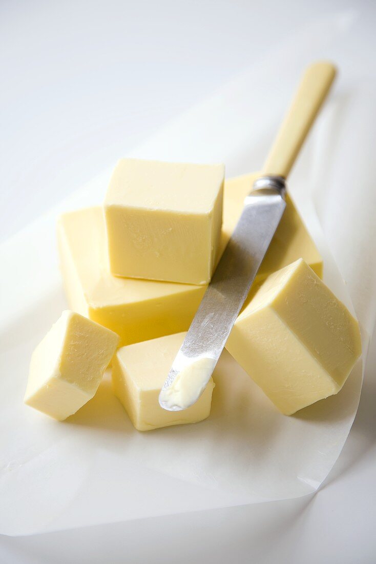 Butter-Würfel auf Papier mit einem Messer