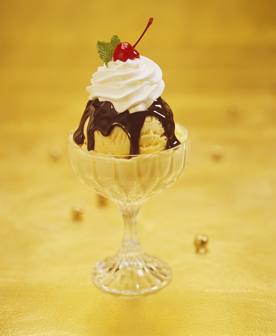 Eisbecher mit Schokosauce, Sahne und Cocktailkirsche