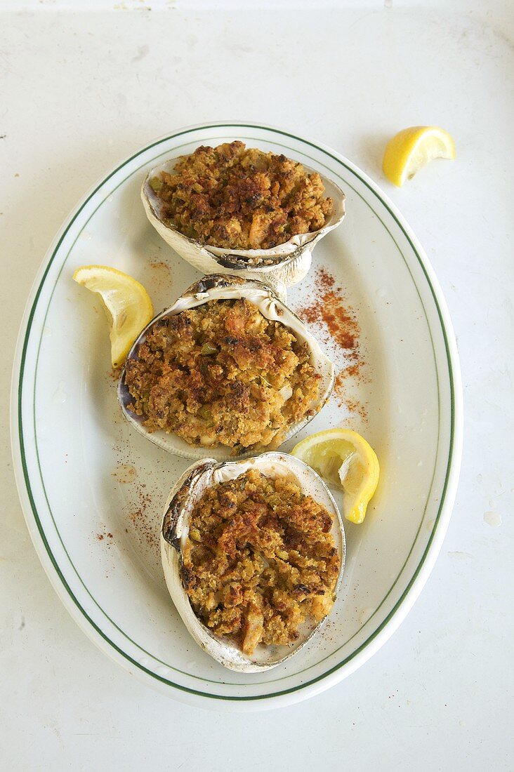 Three Stuffed Clams on a  Plate with Squeezed Lemon Wedges