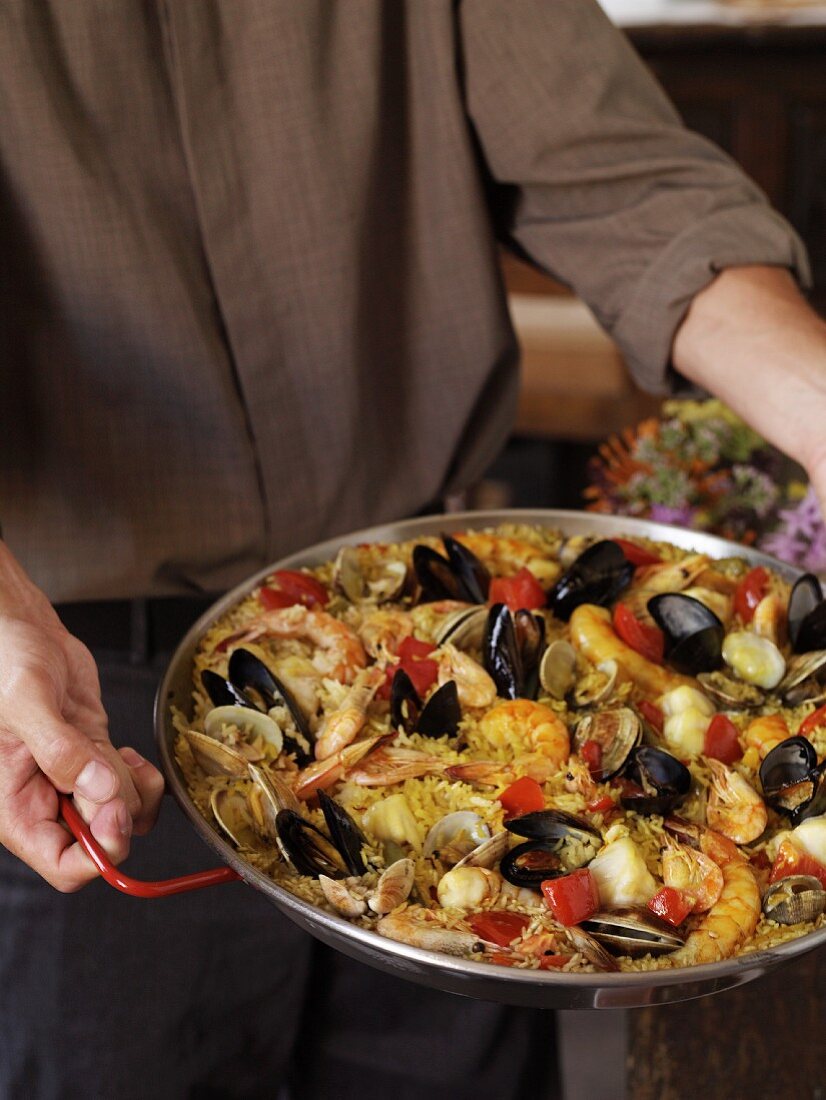Person Carrying a Pan of Paella
