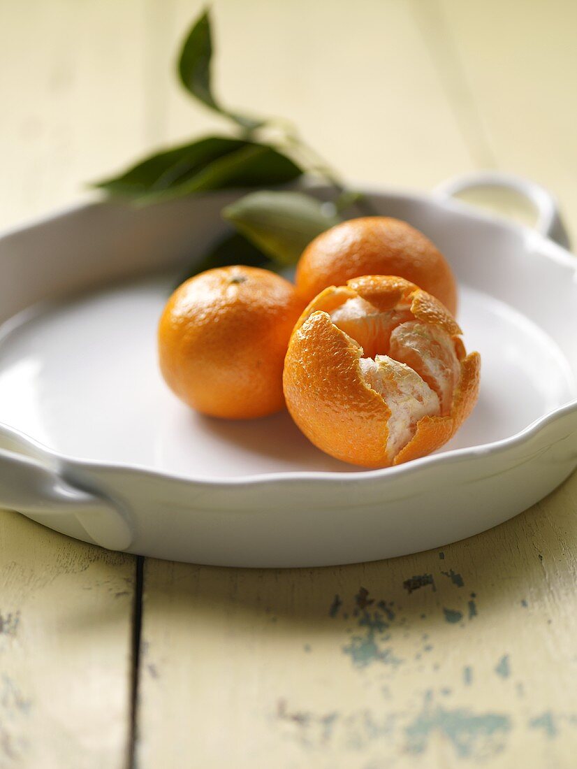 Three Tangerines; One Split Openl On White Dish