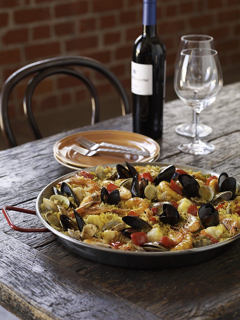 Paella on a Rustic Woden Table with Wine