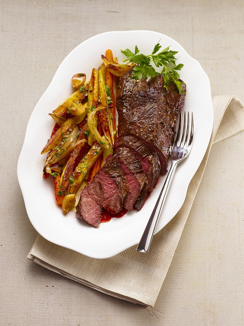 Partially Sliced Steak on a Plate with Roasted Vegetables