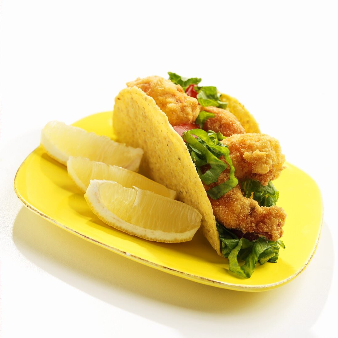 Taco mit frittierten Garnelen und Zitronen auf gelbem Teller
