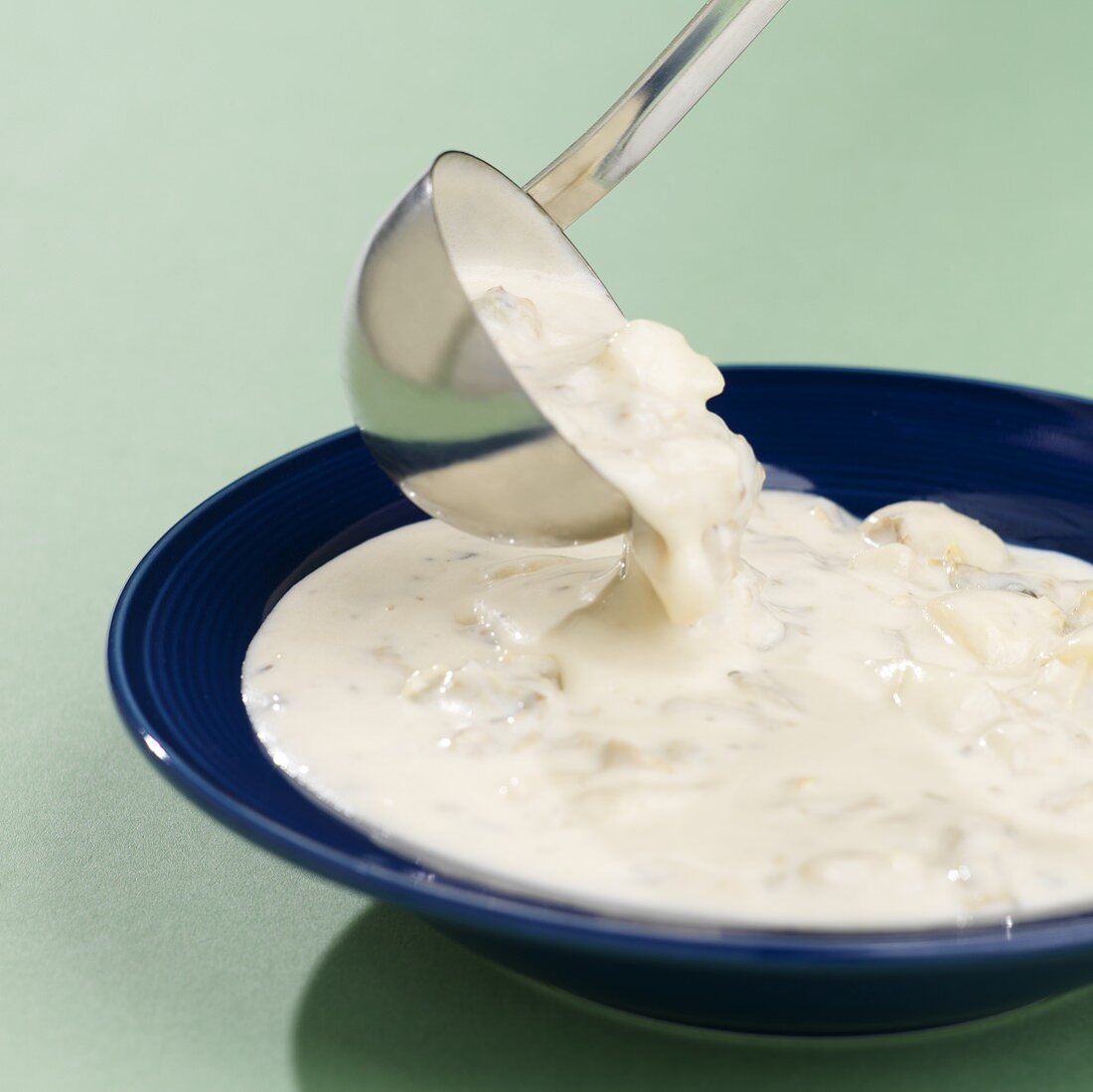 Clam Chowder mit Kelle in Suppenteller gießen