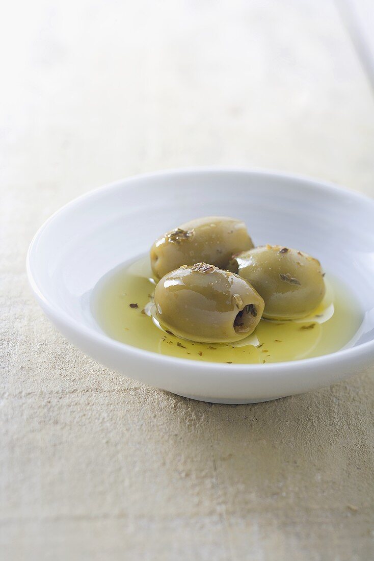 Schälchen mit grünen Oliven und Olivenöl