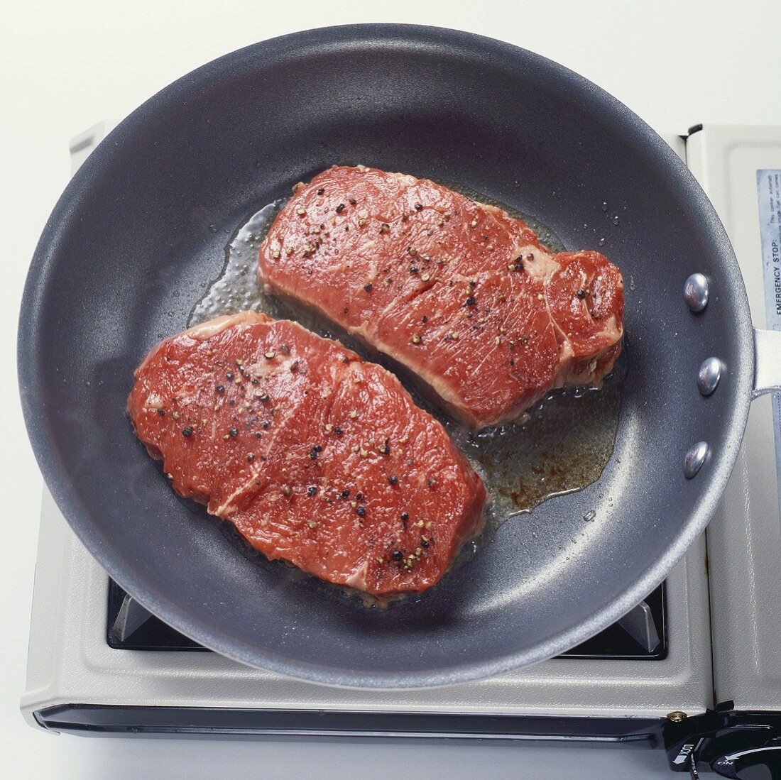 Zwei gepfefferte Steaks in der Pfanne braten