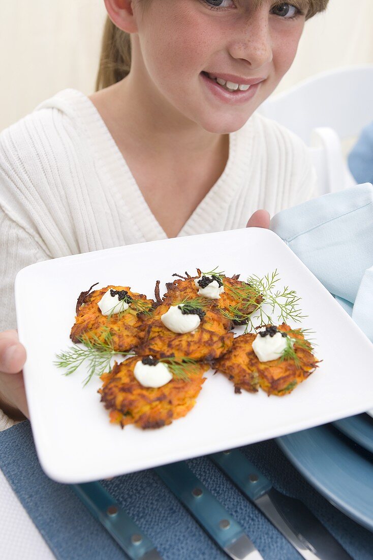 Girl Holding Plate of Carrot Latke with Wasabi Cream and Caviar