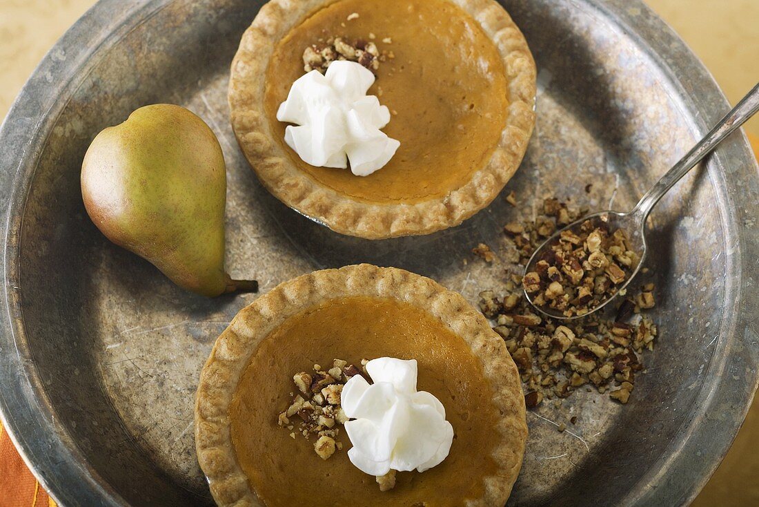 Zwei kleine Pumpkin Pies mit Schlagsahne und Nüssen