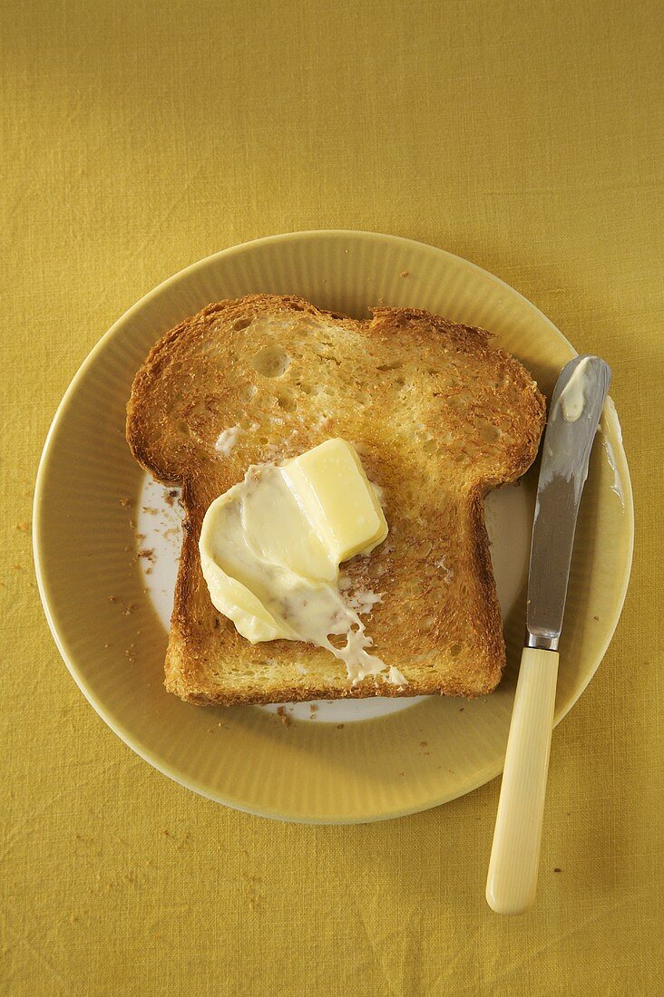 Piece of Toast with Butter on Plate; Knife
