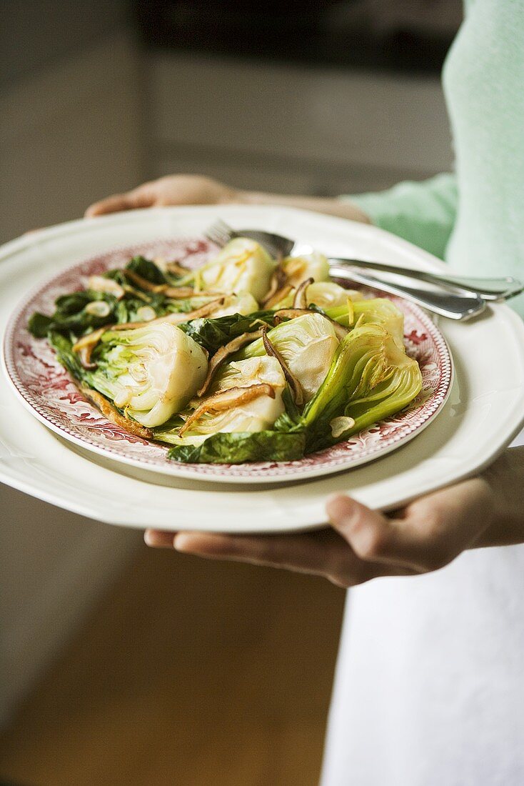 Frau serviert Pak Choi mit Shiitakepilzen