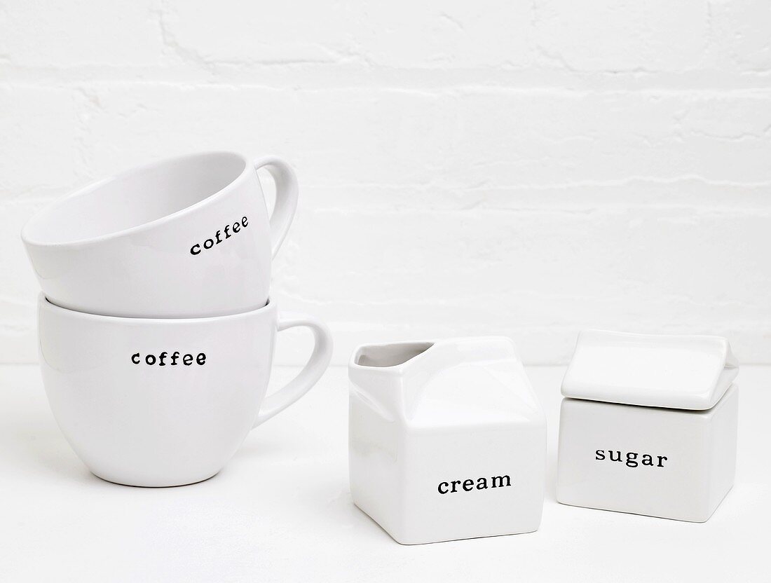 weiße Kaffeetassen, Sahnekännchen, Zuckerdose mit Schrift