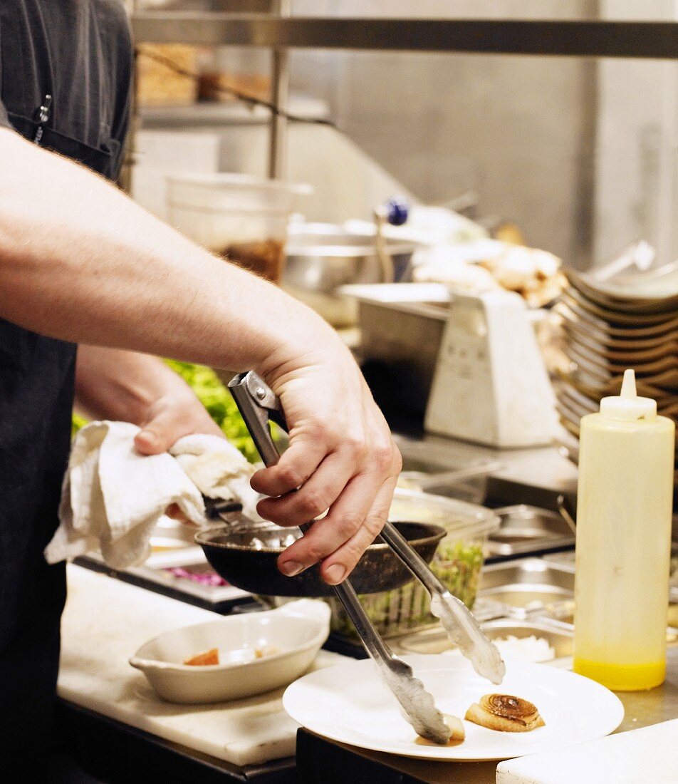 A Chef Plating Food in a Restaurant Kitchen