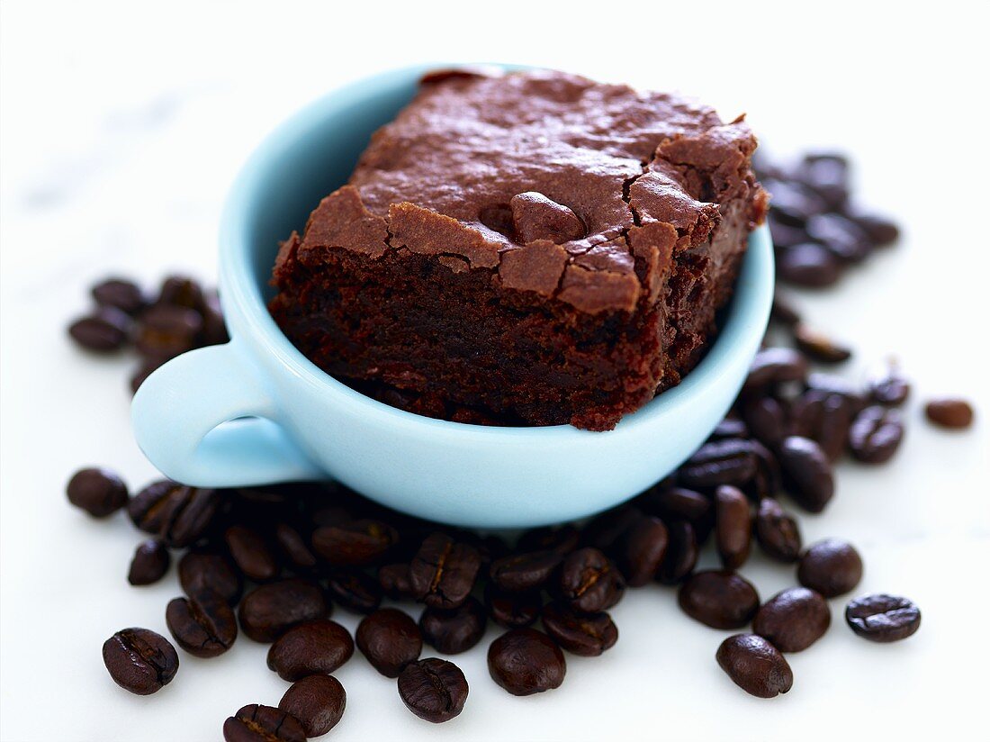 Brownie in Kaffeetasse und Kaffeebohnen