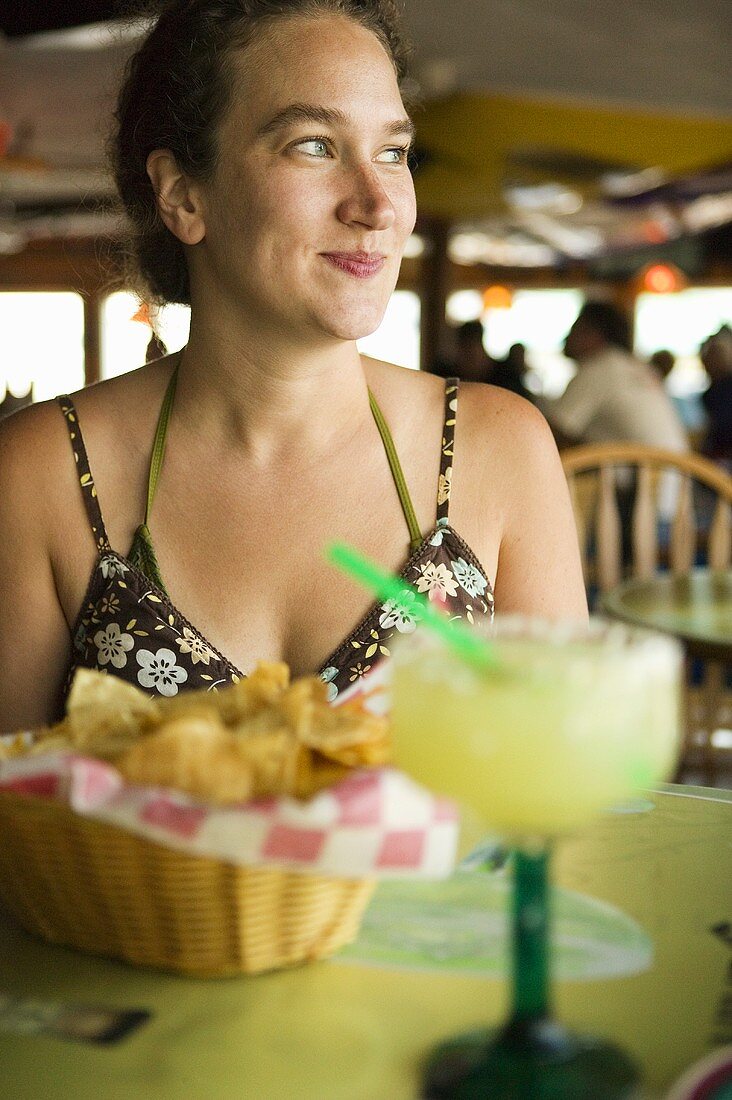 Woman Sitting at Restaurant Table with Margarita and Chips