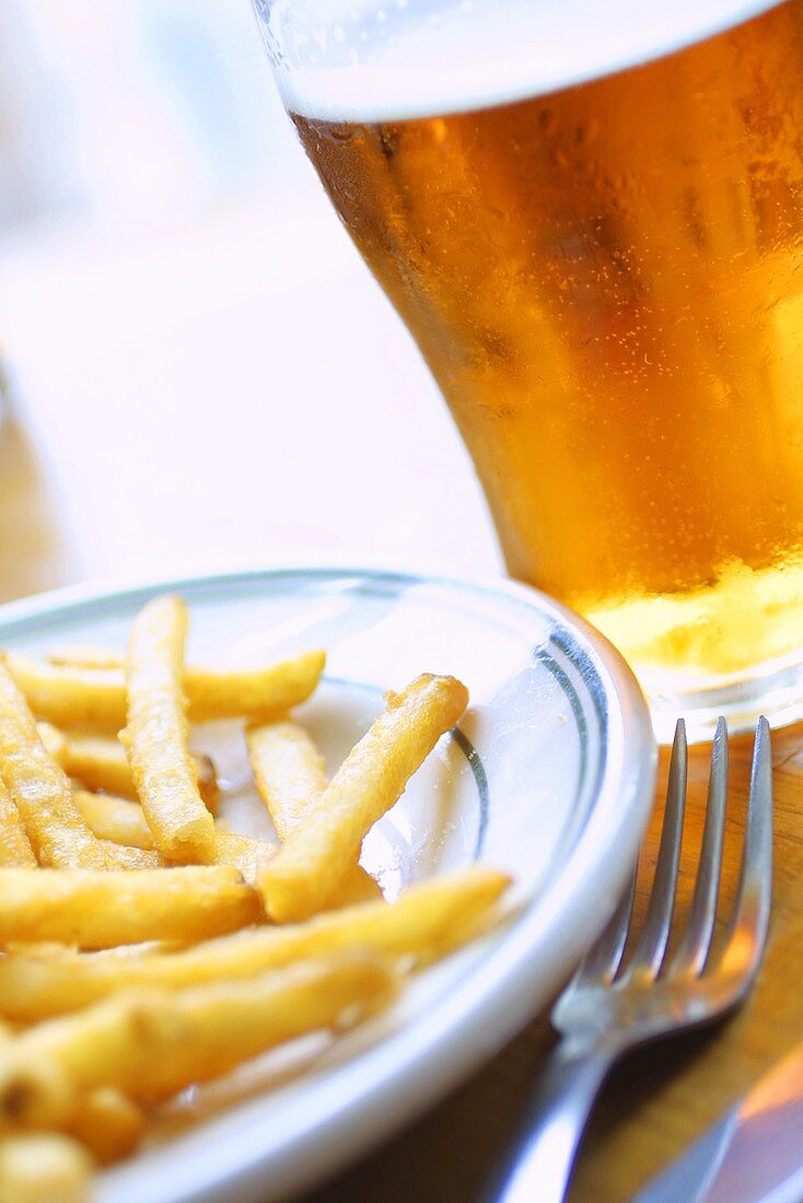 Ein Teller mit Pommes frites und ein Glas Bier