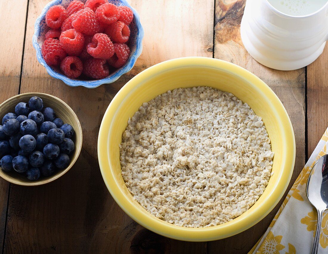 Bowl of Cooked Oatmeal, Organic Berries and Milk on Wooden Table