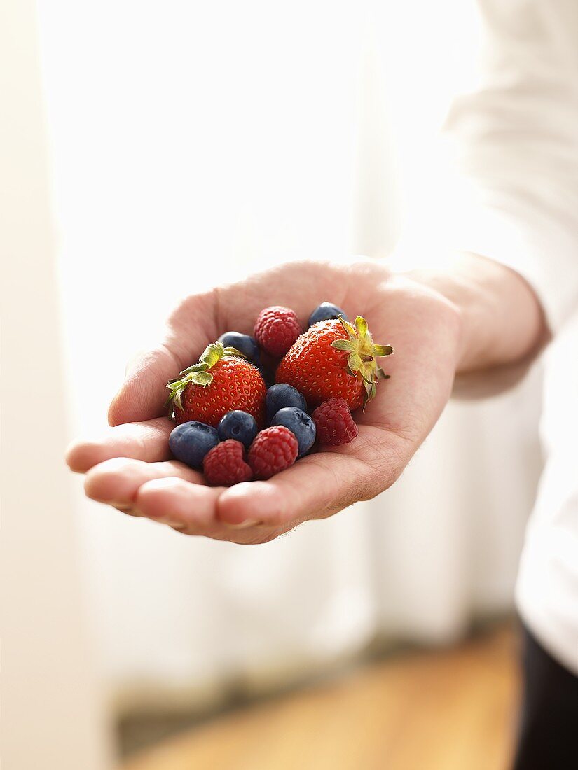 Hand Holding Mixture of Blueberries, Raspberries and Strawberries