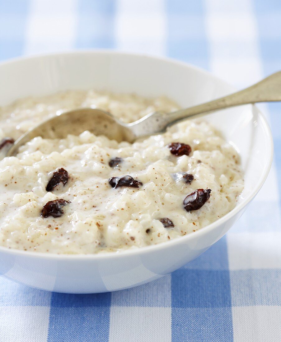 Reispudding mit Rosinen in Schale mit Löffel