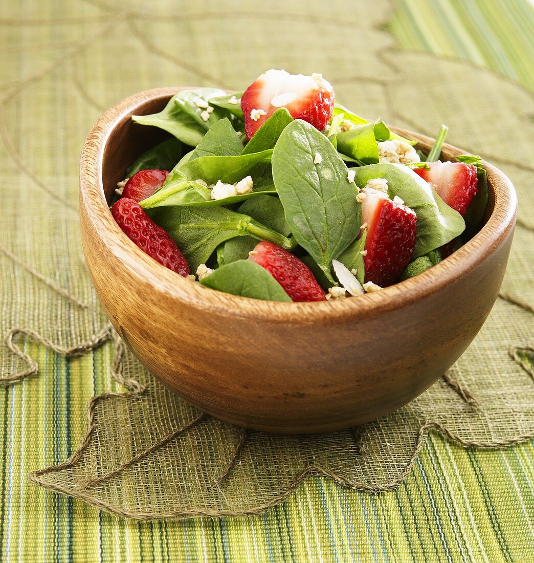 Spinatsalat mit Erdbeeren in Holzschale