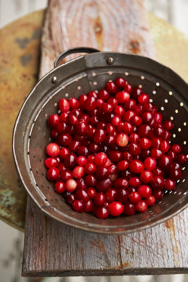Cranberries in Colander on Wooden Table
