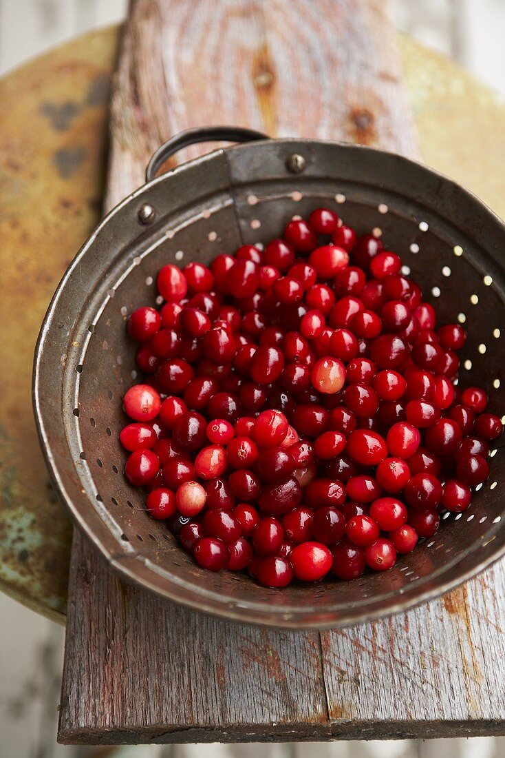 Frisch gewaschene Cranberries im Küchensieb auf Holzbrett