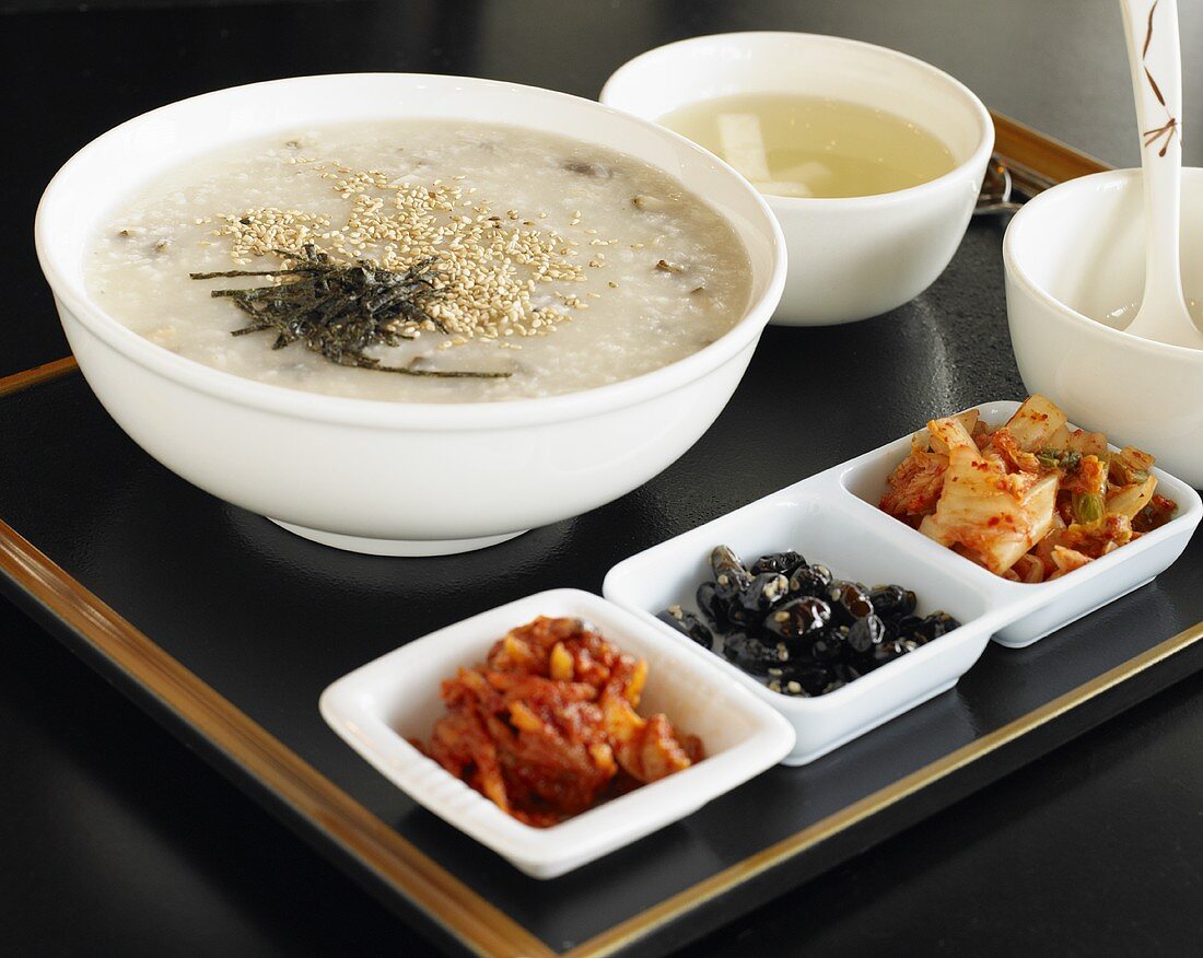Koreanisches Porridge mit Abalone und kleinen Salaten