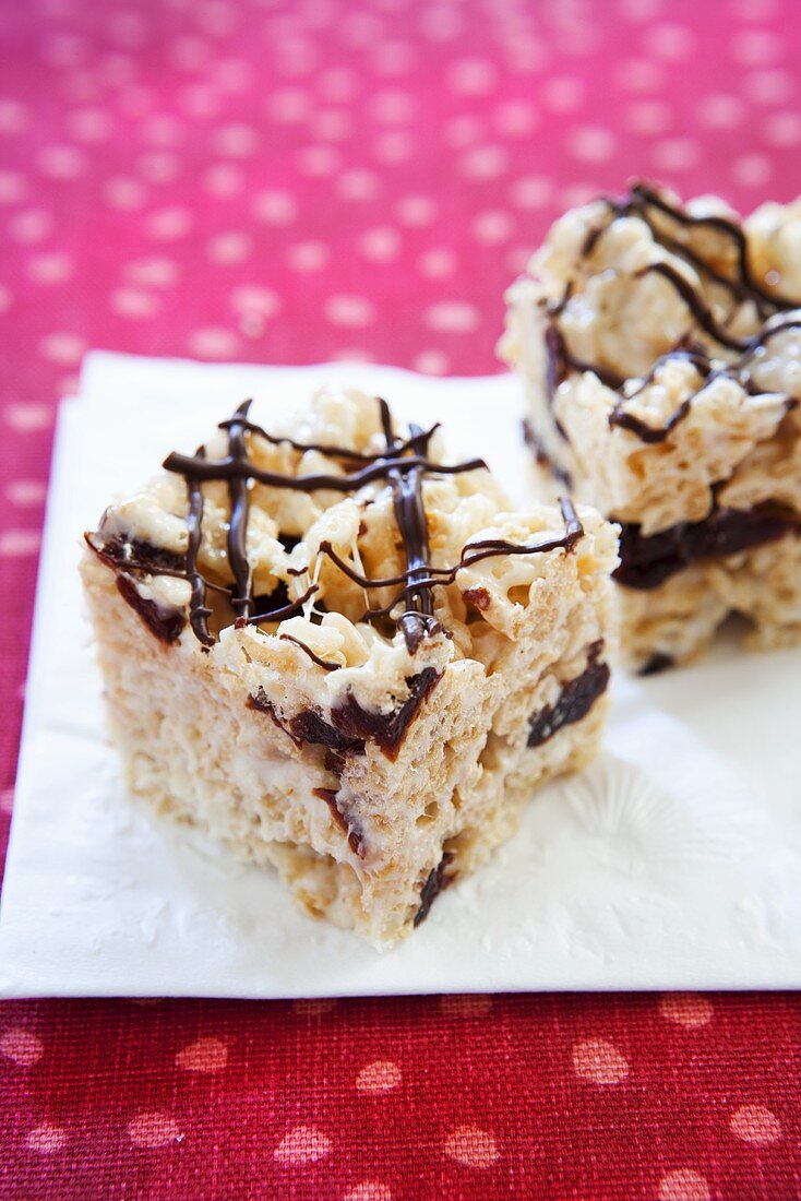 Two Rice Krispie Treats with Chocolate Drizzles on a Napkin