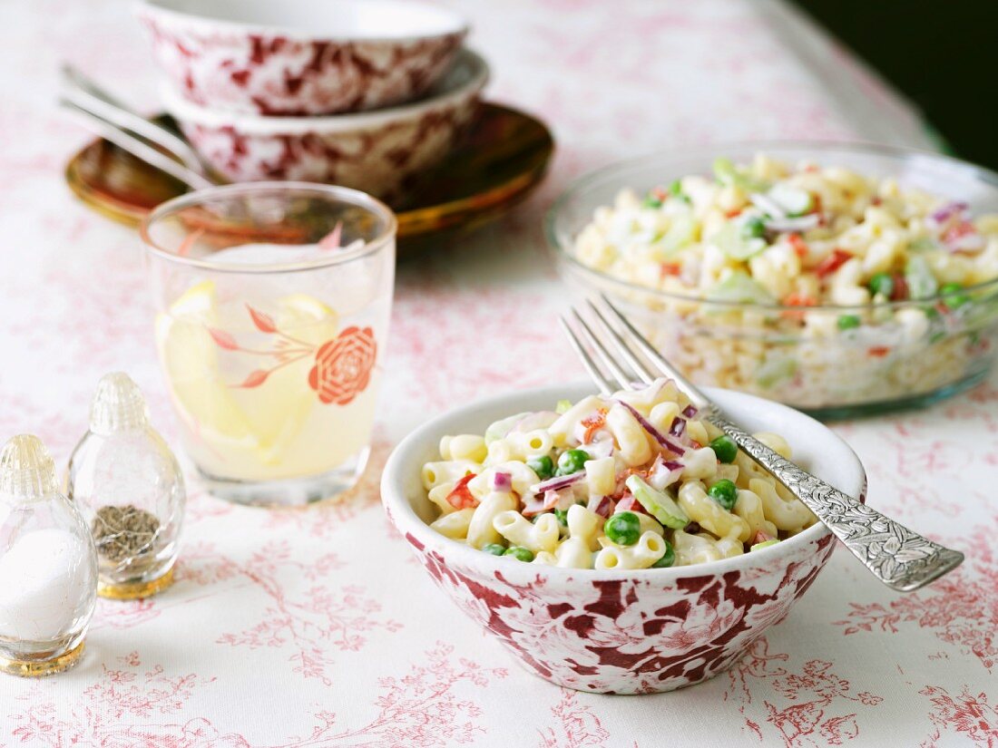 Individual Bowl of Pasta Salad on Table with Serving Bowl