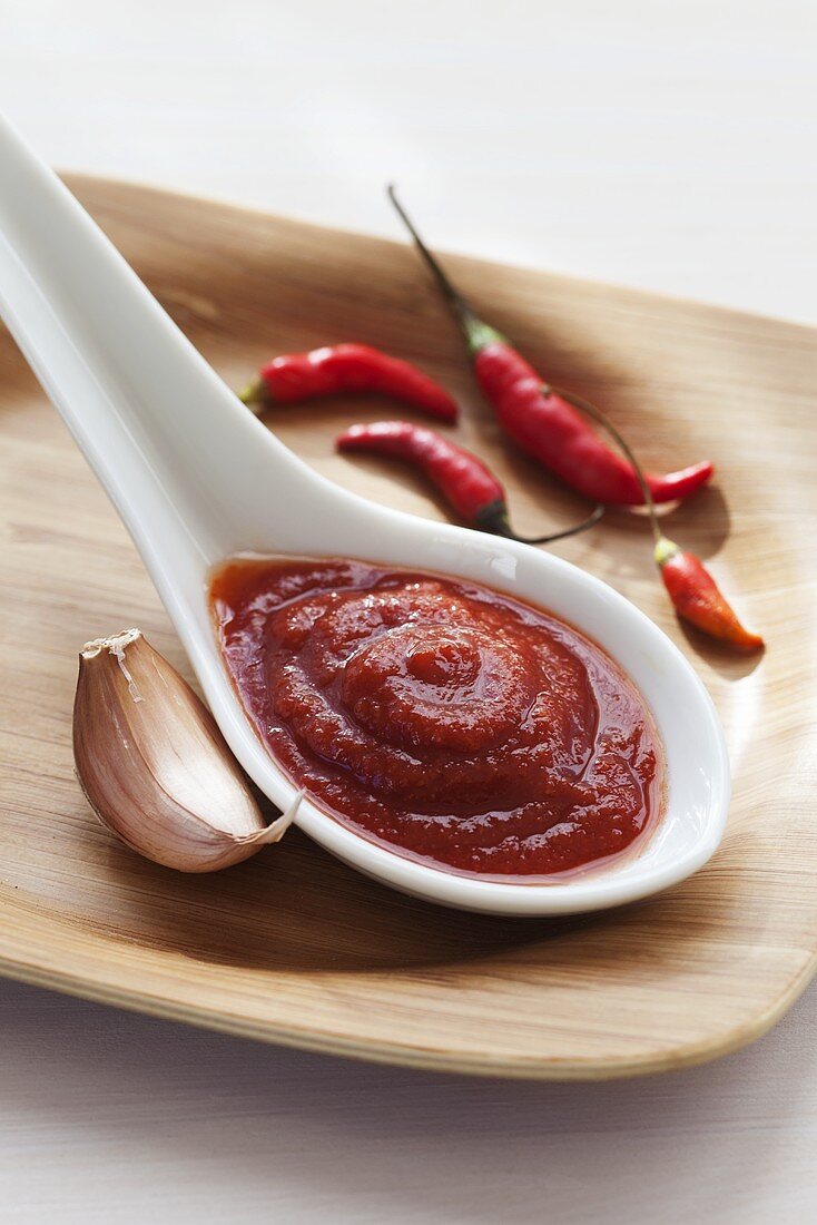 Spoonful of Sriracha Sauce with Garlic Clove and Red Chilis