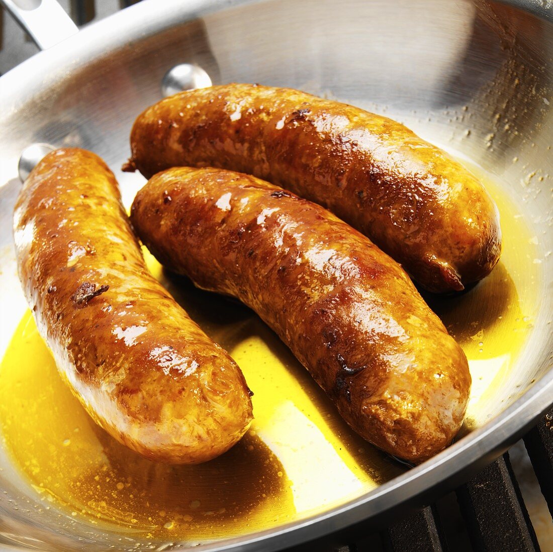Three Browned Italian Spicy Sausages in Skillet with Juices