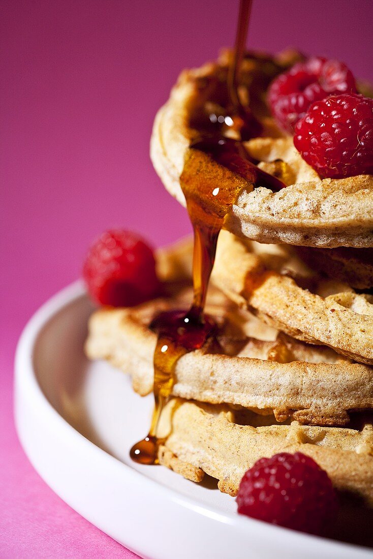 Syrup Pouring Over a Stack of Waffles with Raspberries