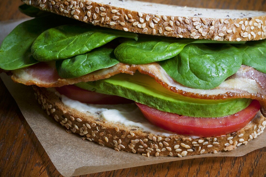 Vollkornbrot-Sandwich mit Bacon, Spinat, Tomate und Avocado (Nahaufnahme)