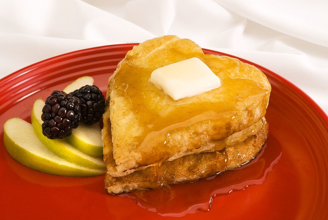 Heart-shaped pancakes with butter and maple syrup, fresh fruit