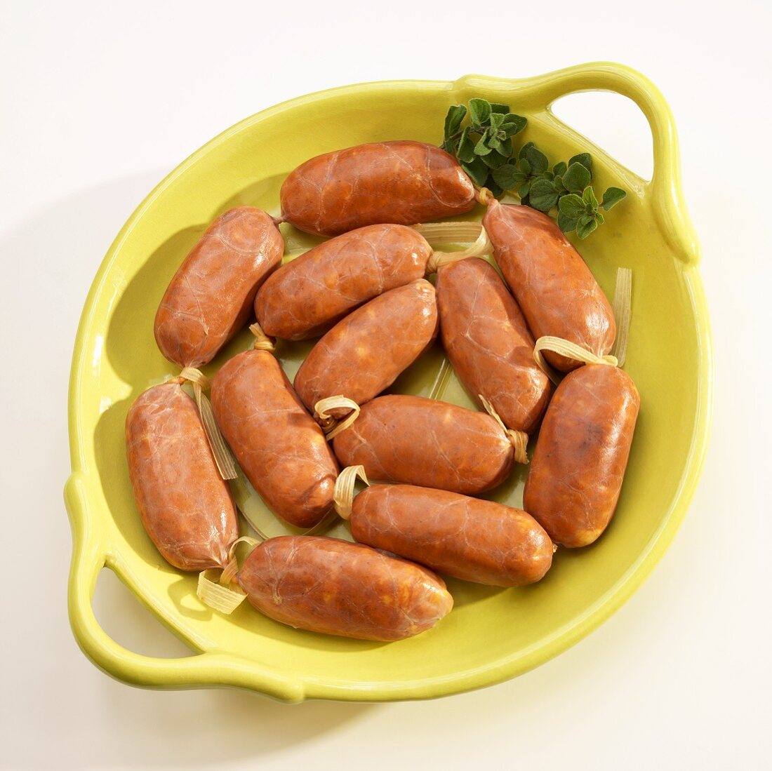 Uncooked Chorizo Links in a Yellow Dish; White Background