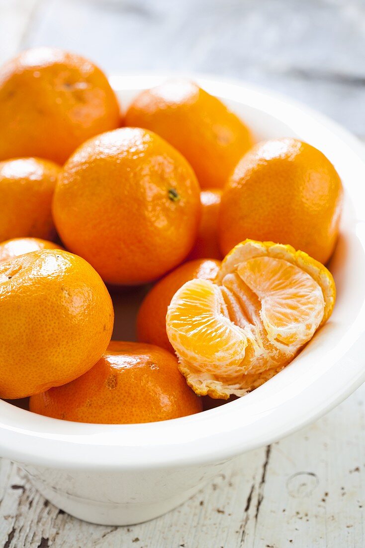 Clementines, one peeled, in bowl