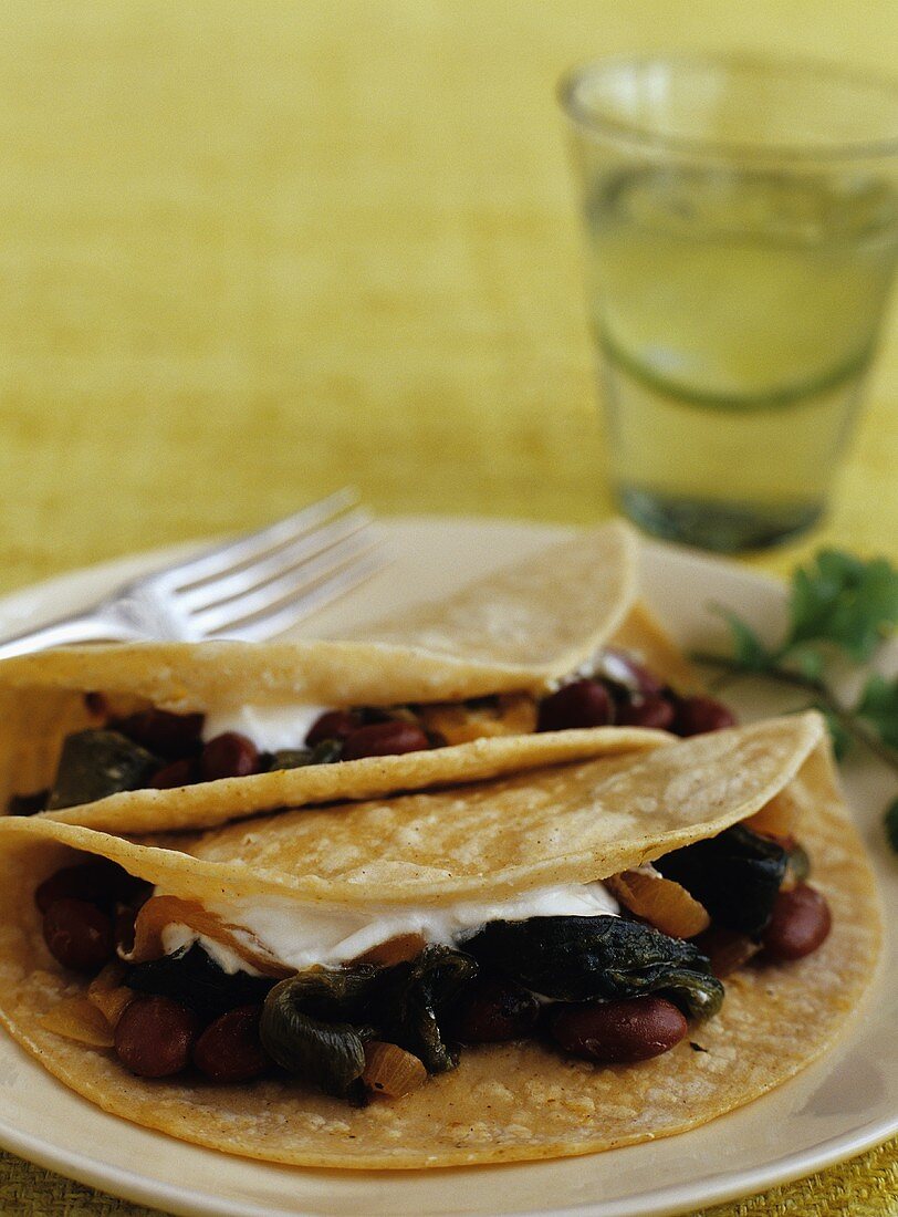 Zwei Tacos mit Pintobohnen und Poblanos, Glas Wasser mit Limetten