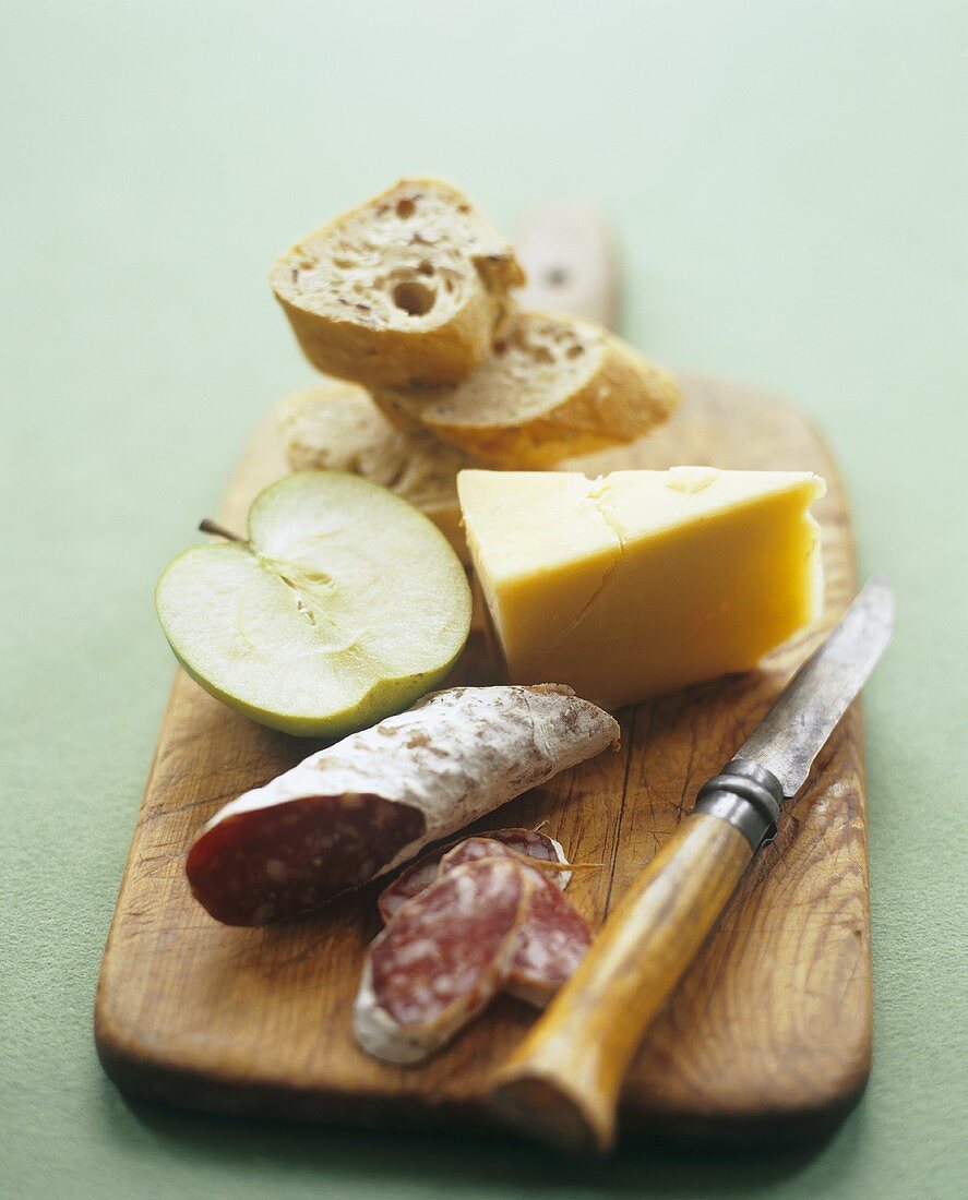 Brotzeit mit Wurst, Käse, Apfel und Brot auf Holzbrett